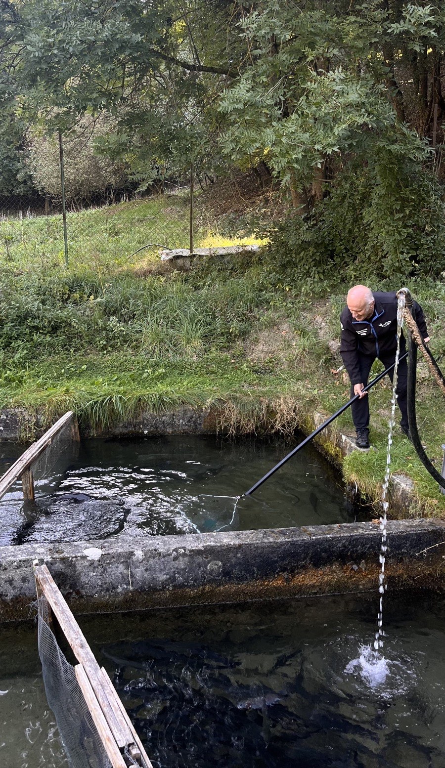 Éleveur de la Pisciculture du Valbonnais au bord des bassins à truites